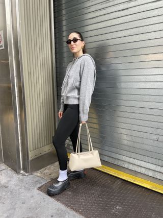 Anna LaPlaca wearing a pair of Sorel x Proenza Schouler Caribou Mules, Freja Christie Bag, Almina Concept wool hoodie, and black leggings