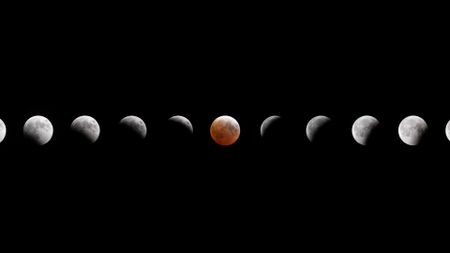 A composite image showing the small gray sphere of the moon across a dark night sky as it reaches various phases of a lunar eclipse. 