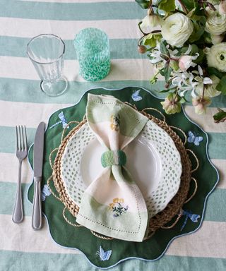 overhead image of place setting with botanical napkin and green stripe tablecloth