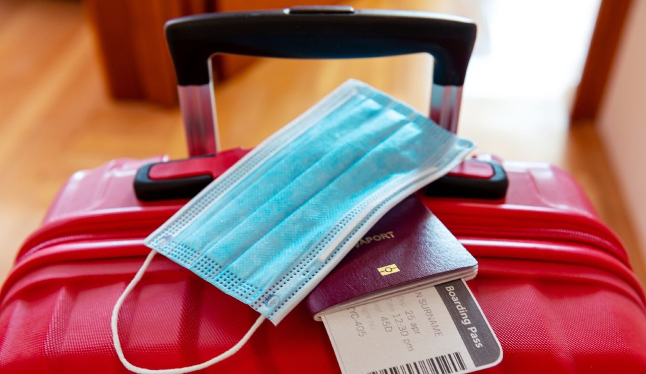 Face protection mask and travel documents over trolley bag. Travel and flight rules during coronavirus pandemic/Delta Variant crisis in Europe and world