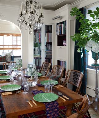 Dining room with wooden dining table and chairs, chandelier and plaid curtain and rug
