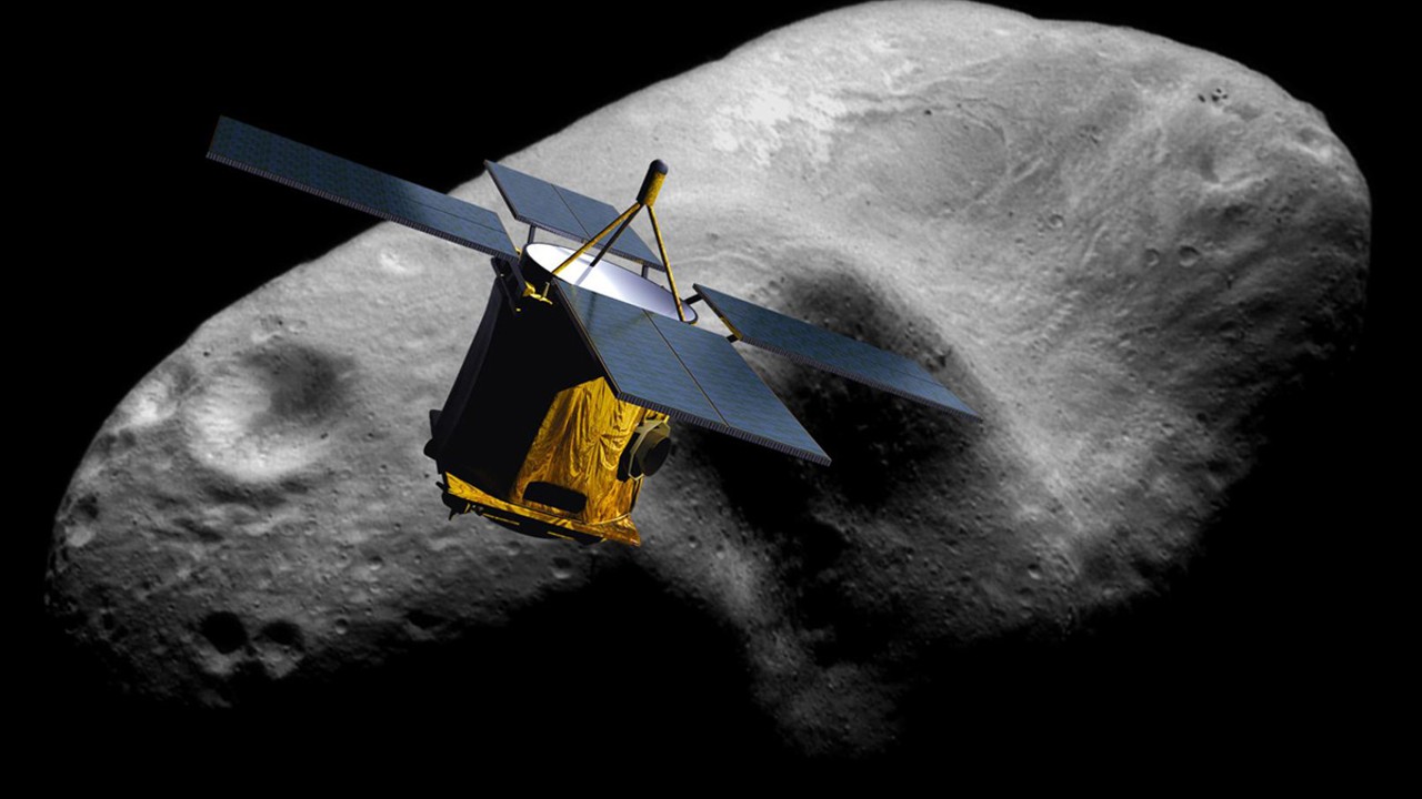 a cube-shaped spacecraft with four solar panels flies near a lumpy grey rock on a black background