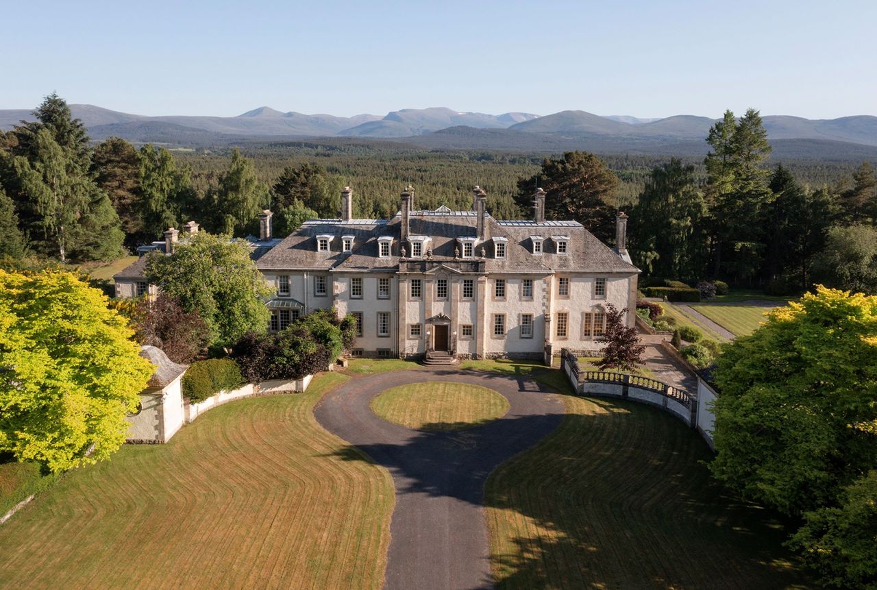 The front of the property shows a circular driveway and grassy banks either side
