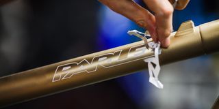 A hand peels away the paint from a Parlee logo on a gold bike frame