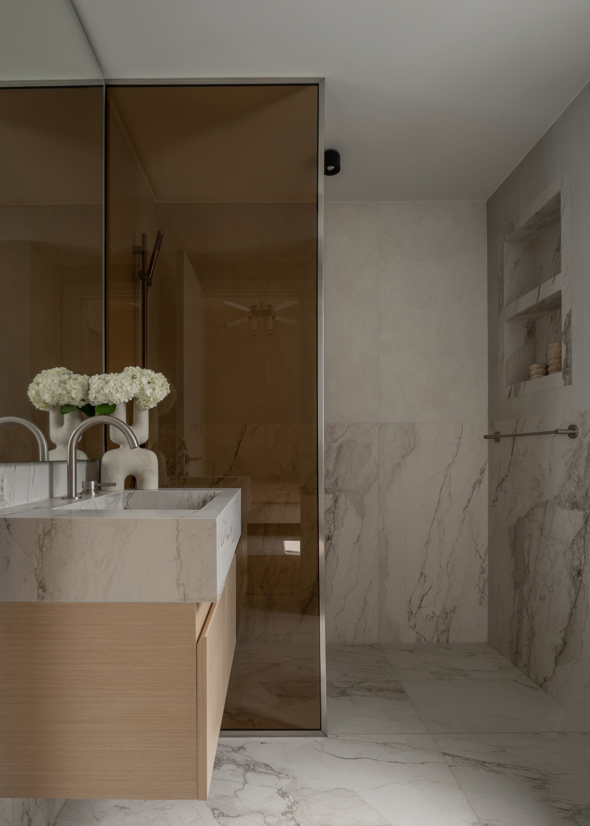 A neutral stone bathroom with an amber glass shower room