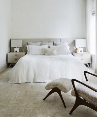 A white bedroom with tonal neutral carpet and bed linen illustrating simple bedroom decor ideas.