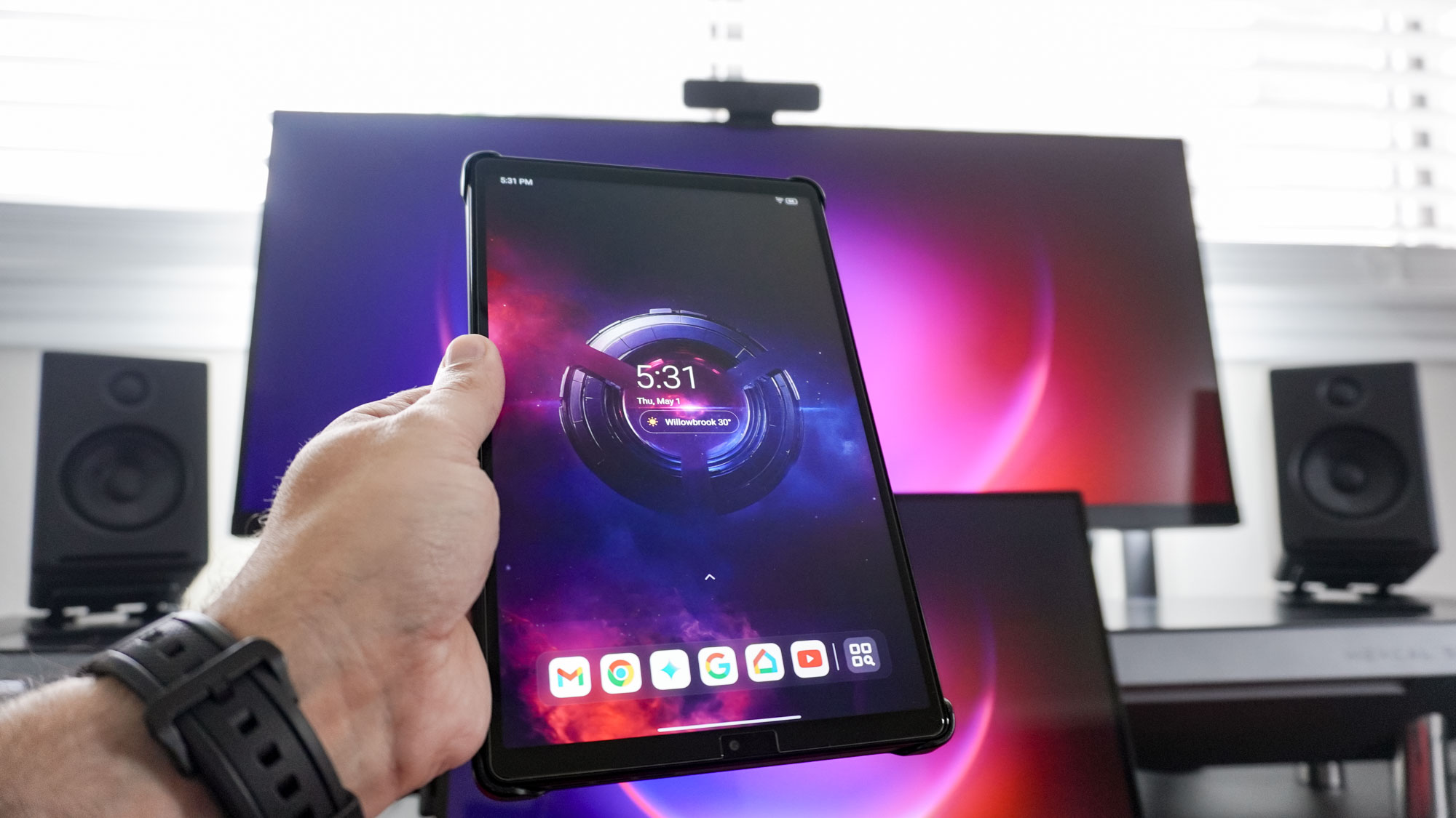 A person holding the Lenovo Legion Tab Gen 3 in portrait mode in front of a desk setup