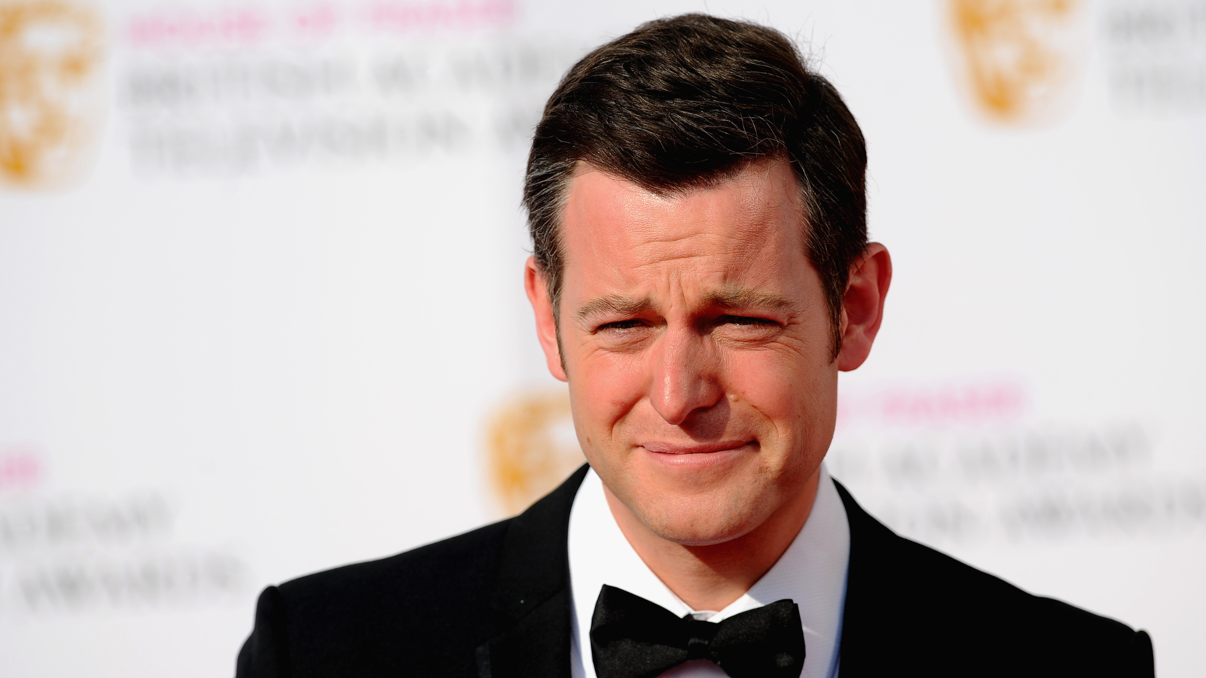 Matt Baker in black tie on red carpet.