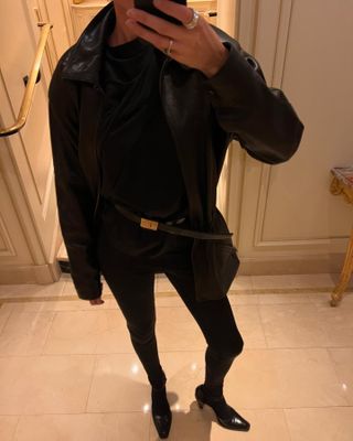 Elly McGaw wearing a leather jacket, YSL belt, tights, and block-heel shoes.