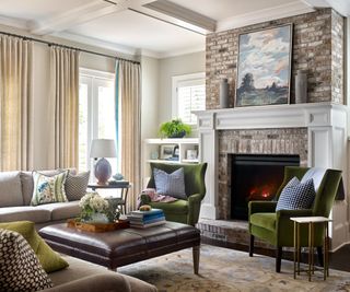 living room with stone fire surround and beige sofas with green armchairs