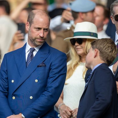 Prince George and Prince William wearing blue blazers at a Wimbledon match