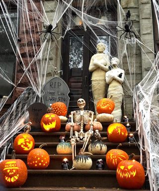 Halloween door decorating idea with skeleton and mummy figures, carved pumpkins and webbing
