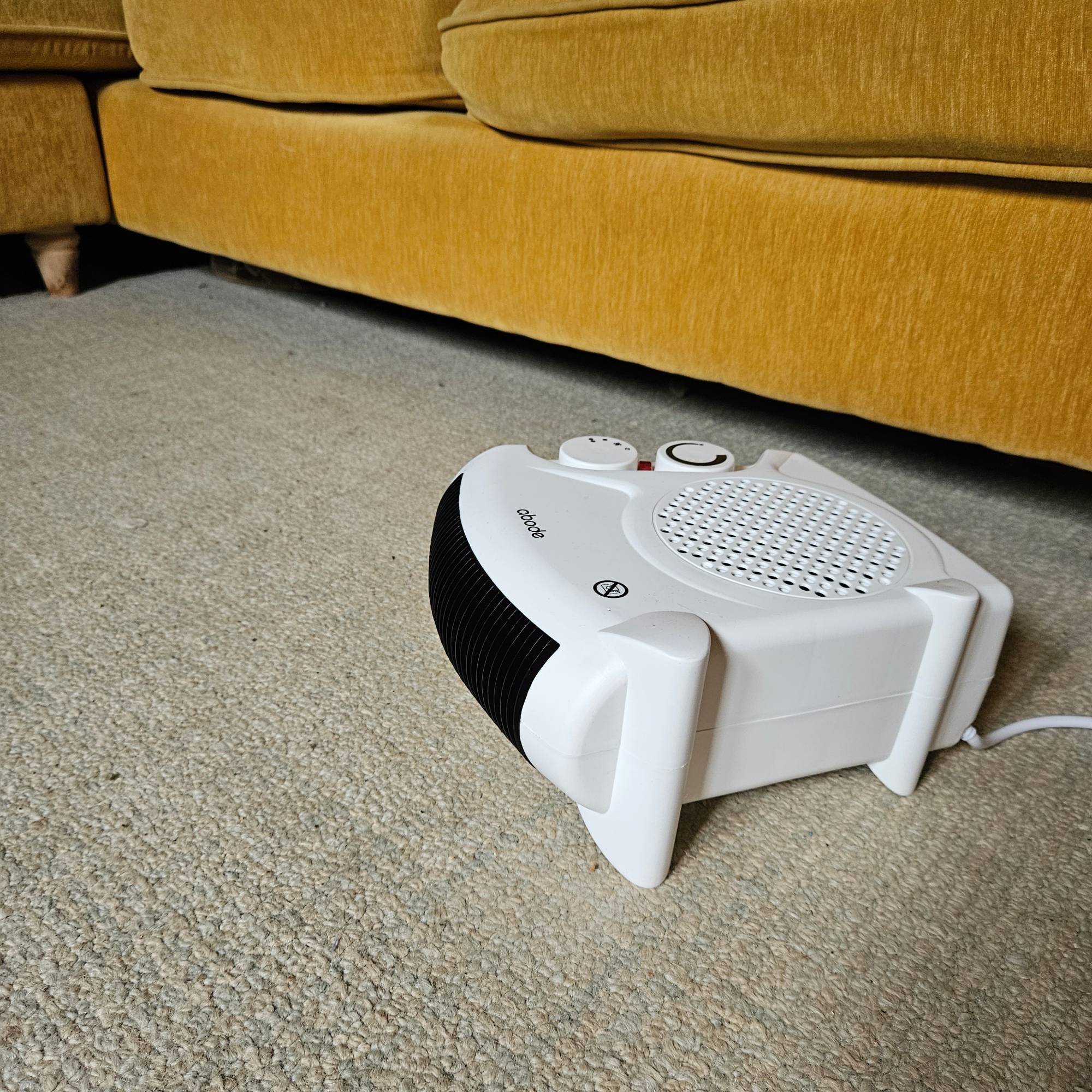 white fan heater in use next to yellow sofa