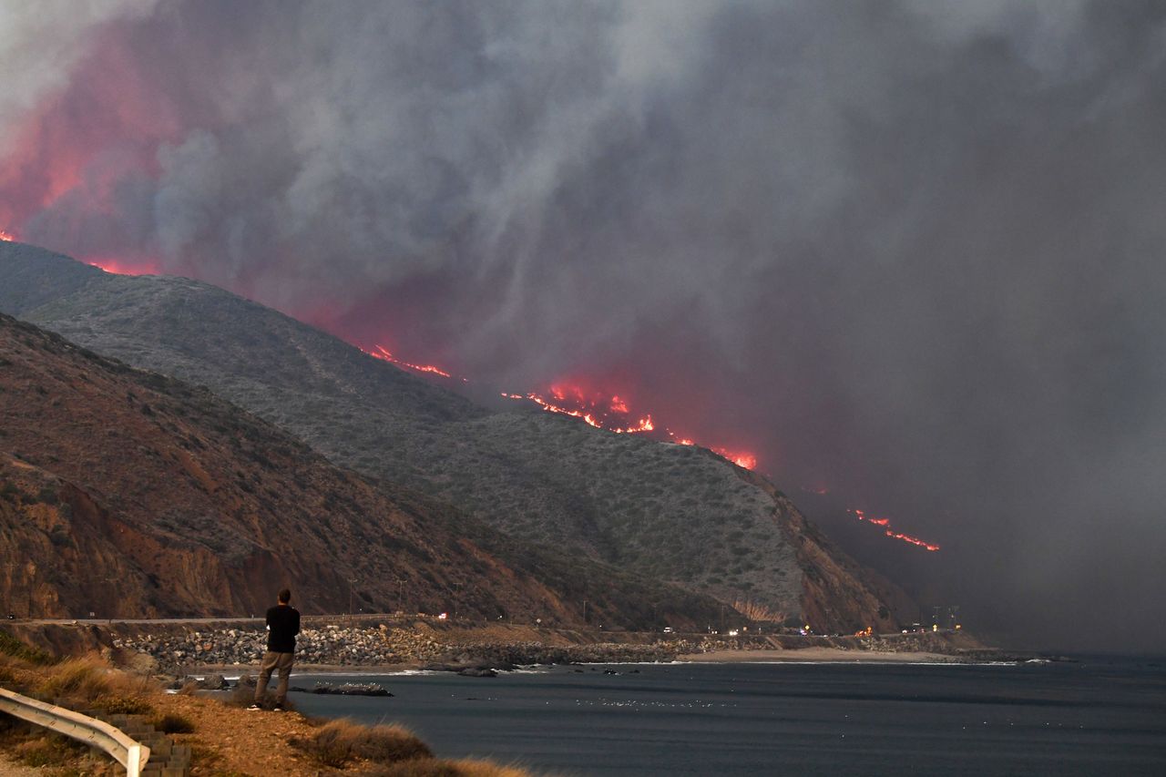 A man watches as the Woolsey Fire reaches the ocean along Pacific Coast Highway (Highway 1) near Malibu, California, November 9, 2018. 