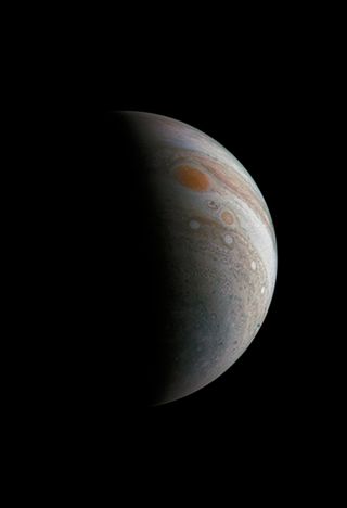 An image of Jupiter in a crescent shape, with its famous Red Spot prominent.