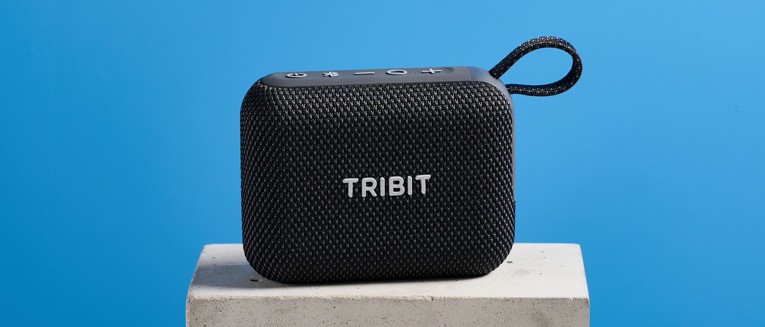 The Tribit PocketGo speaker in black photographed on a blue background. 
