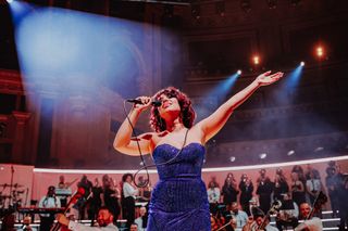 raye wearing a blue long dress performing live at albert hall