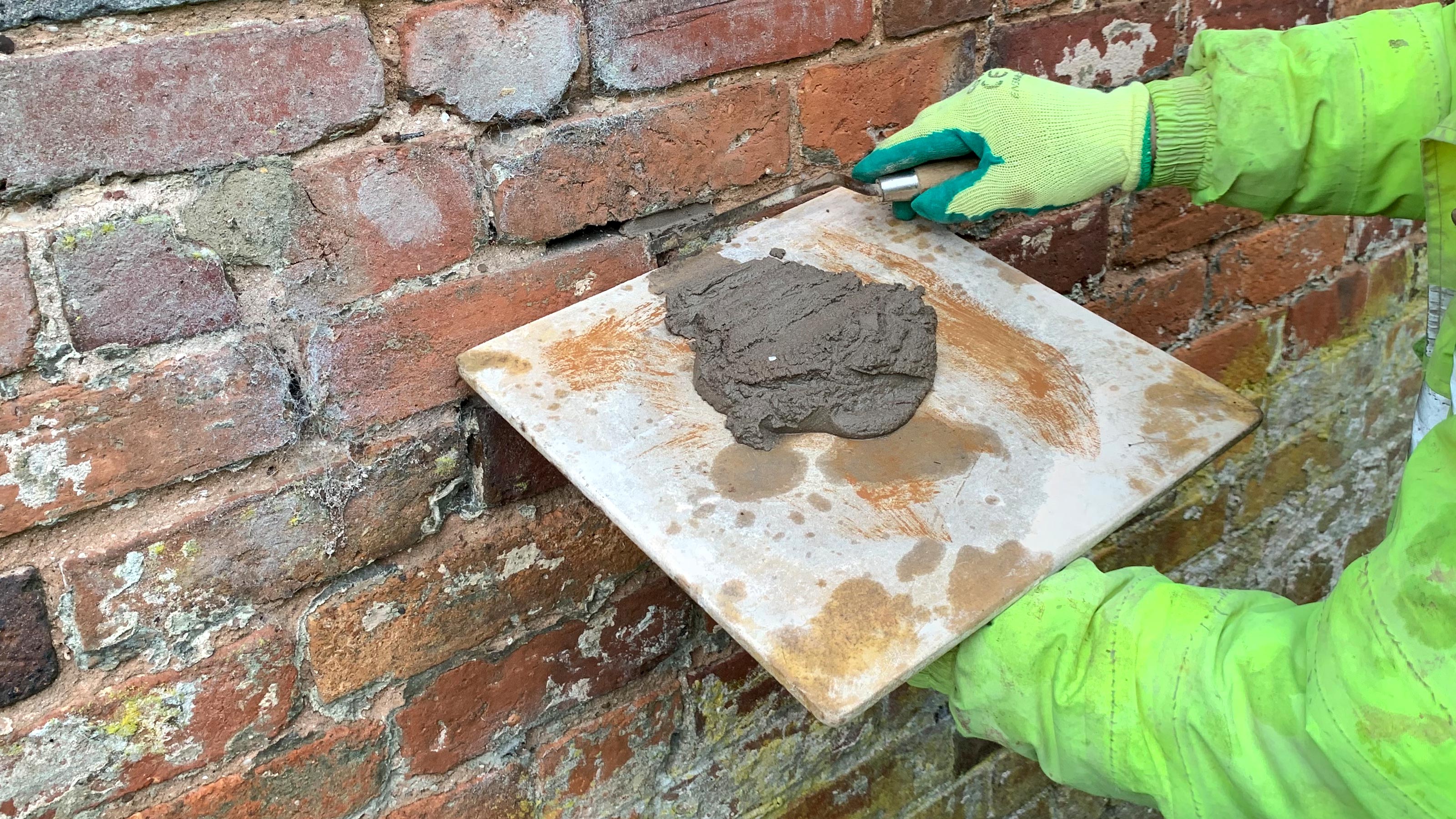 Nahaufnahme von Hawk mit Mörtel auf gegen Mauer