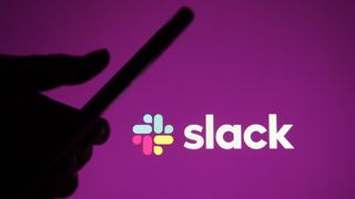 The Slack logo on a purple background in front of a silhouette of somebody on their phone