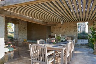covered pergola with beams and sticks and space for alfresco dining