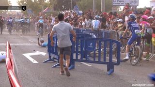 A member of the Vuelta a Espana organisation runs to remove barriers