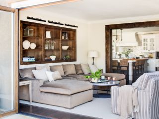 living room with large glazed doors, cream walls and chocolate colored sofa