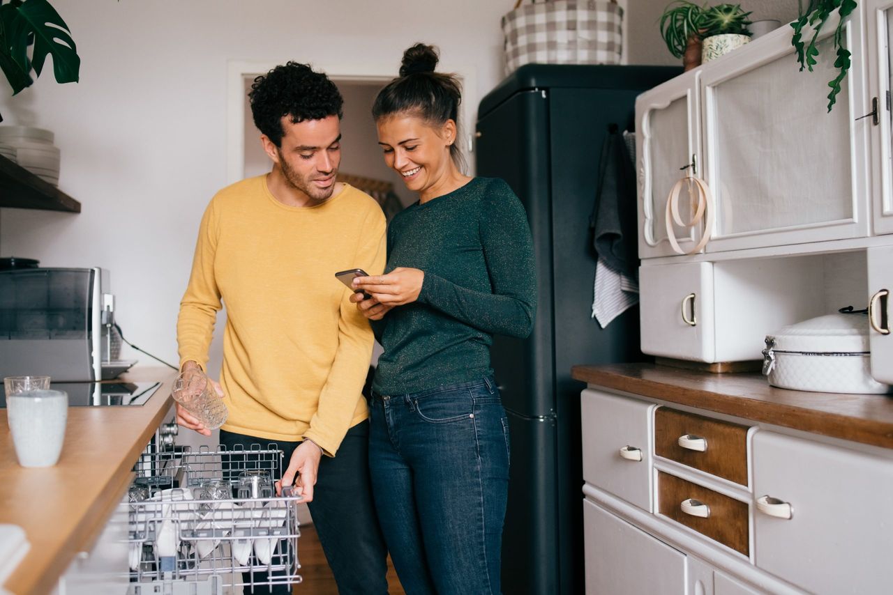 Man and woman looking at a phone, finding out how to save money on electric bills