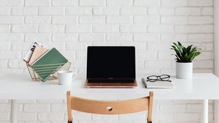a laptop on a white desk in front of a white brick wall