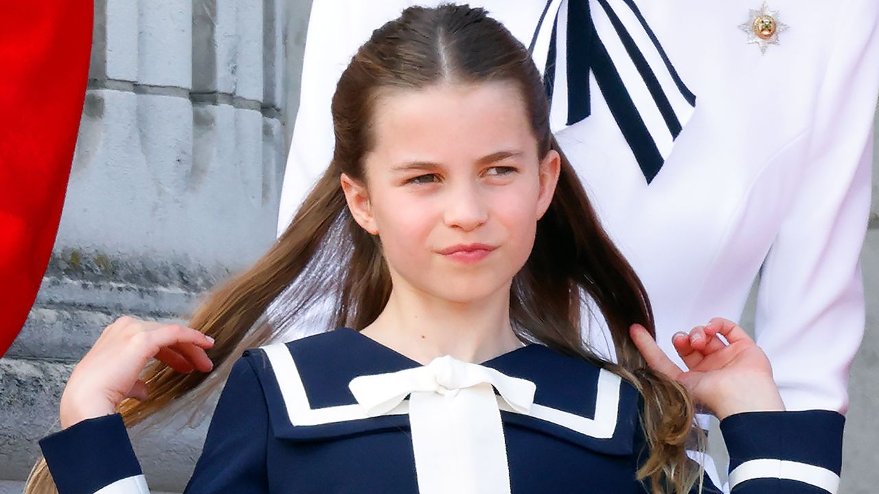 Princess Charlotte flips back her hair as she watches an RAF flypast from the balcony of Buckingham Palace after attending Trooping the Colour on June 15, 2024