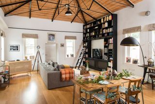 open plan living and dining area with high wooden ceilings and a bookcase