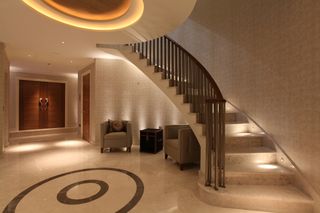 Hallway with grand curved staircase with lighting and neutral decor