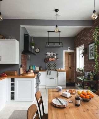 A grey and white kitchen with exposed brick walls