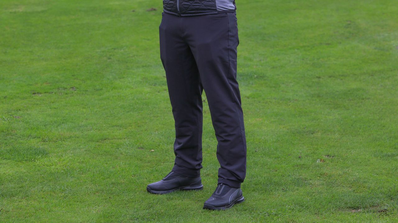 The Puma DRYLBL Rain Waterproof Golf Pants on a green background