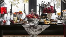 Halloween table with black and white toile runner, chrome serveware, and skull-shaped vases