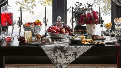 Halloween table with black and white toile runner, chrome serveware, and skull-shaped vases
