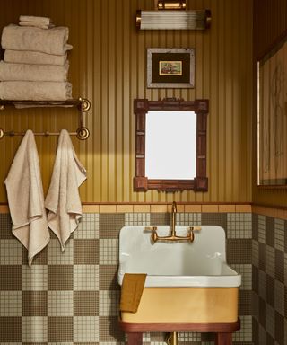 Vintage bathroom with mustard wall paneling, geometric floor tile and brass fixtures for art deco feel