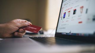 Person holding a credit card next to laptop - new payments technology