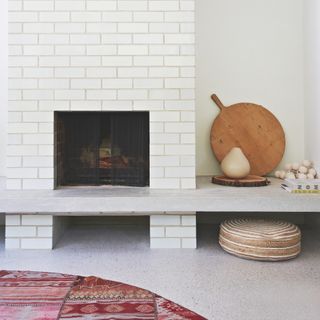 modern white painted brick chimney breast with a concrete shelf across the span of the white living room