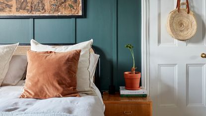 Teal bedroom with wooden bedside table and linen bedding