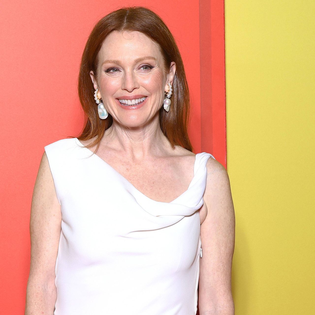 Julianne Moore smiles in front of a pink and yellow wall