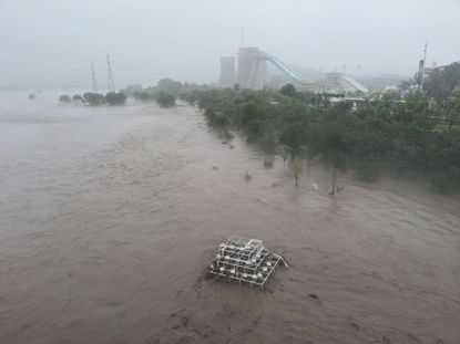 Flood waters run through the Shougang Bridge in Beijing