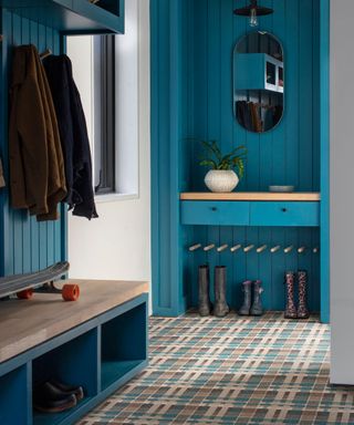 Blue bootroom with painted cabinetry, blue tartan carpet, shoes and coats stored