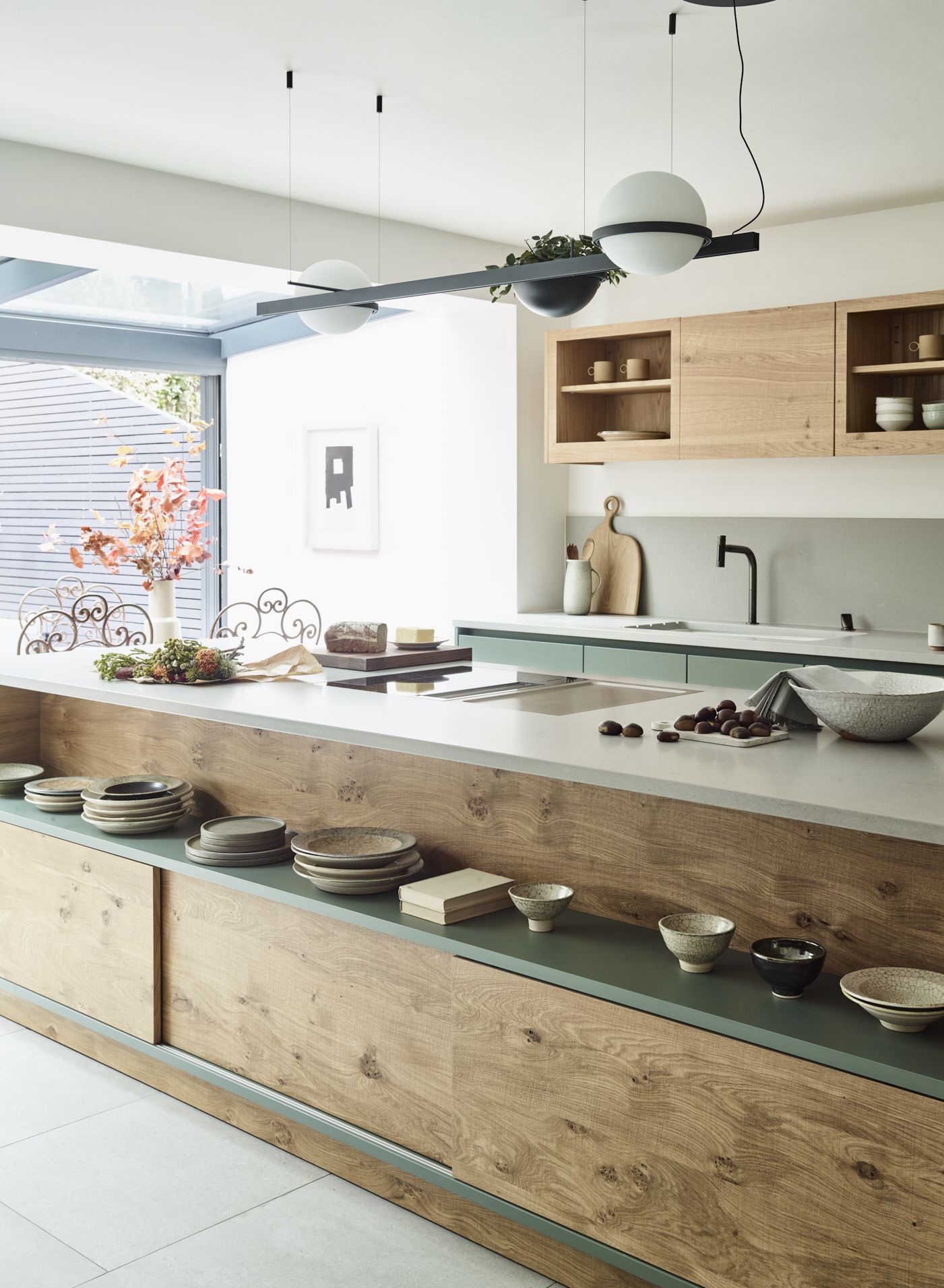 Kitchen with green and wood cabinetry, large island unit, tile floor and white wall