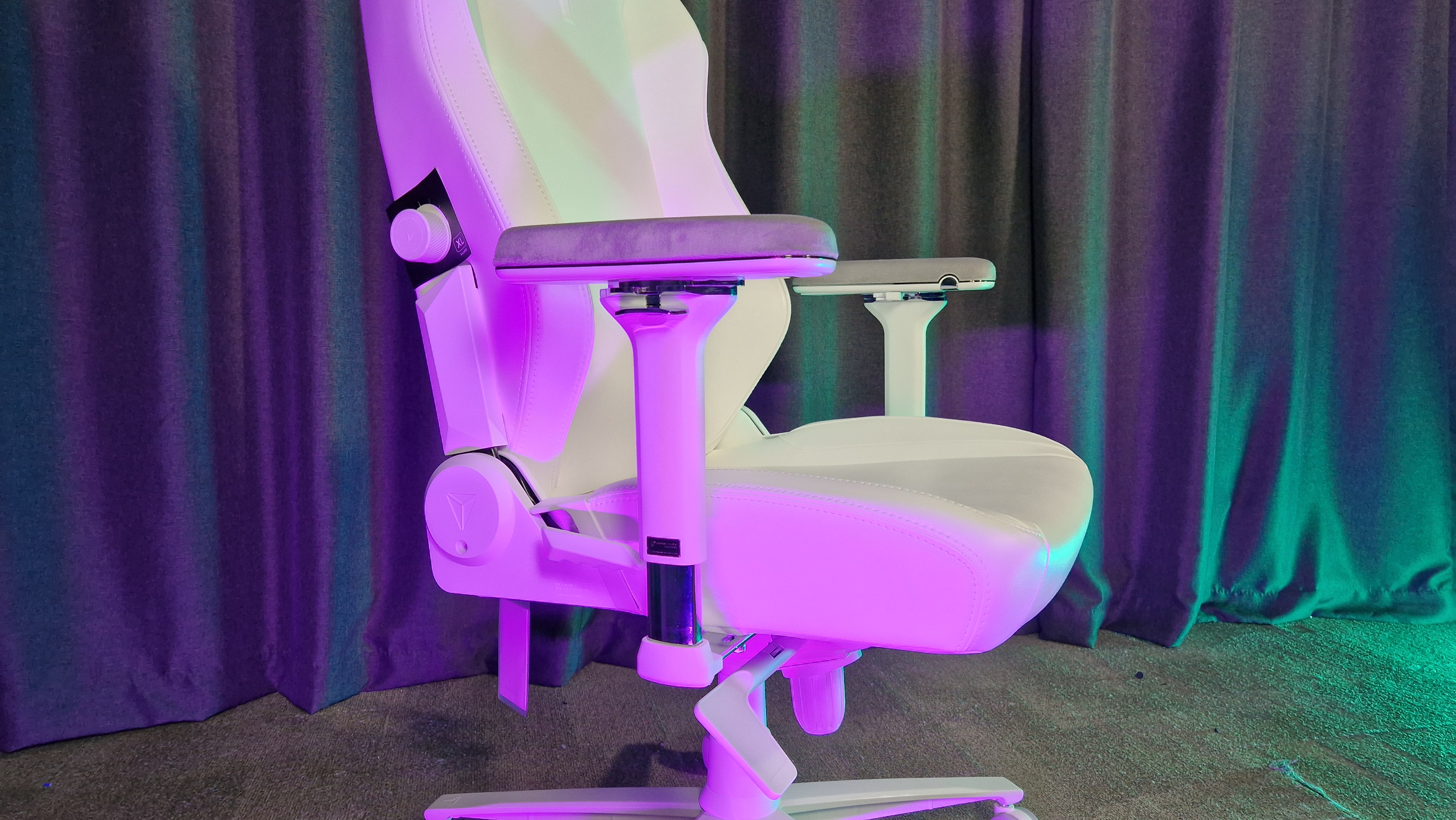 The Secretlab Titan Evo NanoGen Edition chair on a grey floor with grey curtains behind it