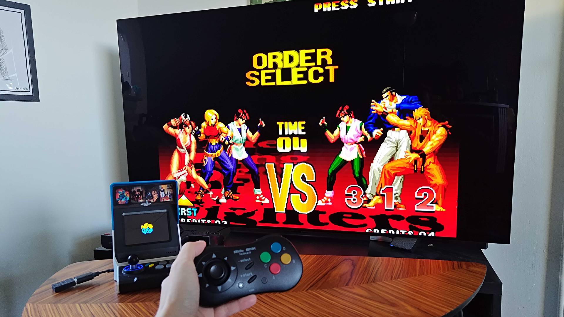 Neo Geo Mini plugged into LG OLED C4 TV with King of Fighters character select on screen.