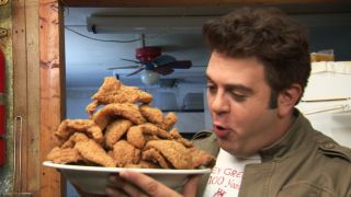 Adam Richman staring at a plate full of fried catfish