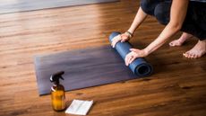 Woman rolling up a yoga mat after cleaning