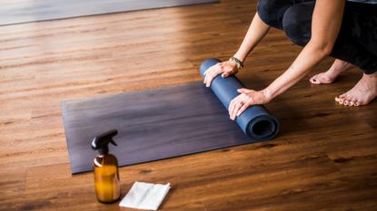 Woman rolling up a yoga mat after cleaning