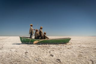 people in a boat with oars in a desert