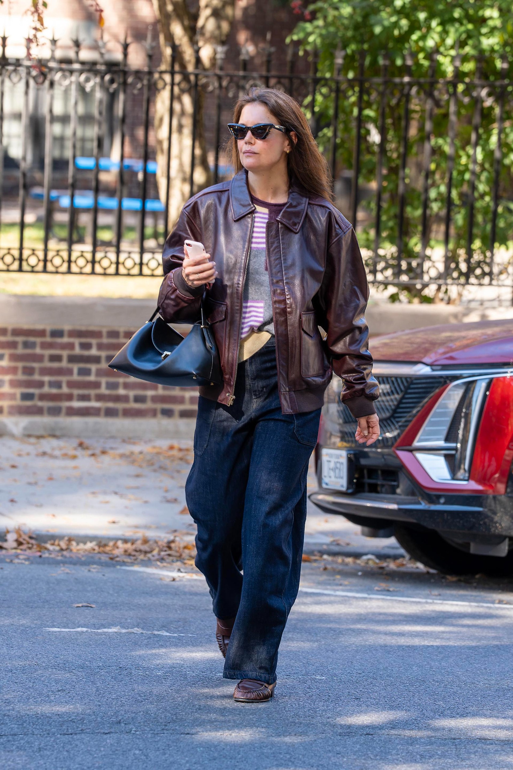 Katie Holmes wears a burgundy leather jacket by Banana Republic along with barrel jeans and loafers